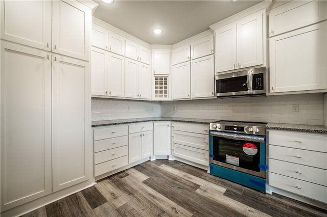 kitchen featuring white cabinetry, dark hardwood / wood-style flooring, stainless steel appliances, and dark stone countertops