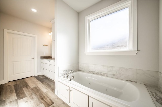 bathroom featuring tiled tub, vanity, and hardwood / wood-style floors