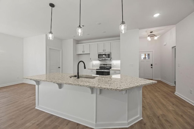 kitchen featuring wood finished floors, appliances with stainless steel finishes, a breakfast bar area, and a sink