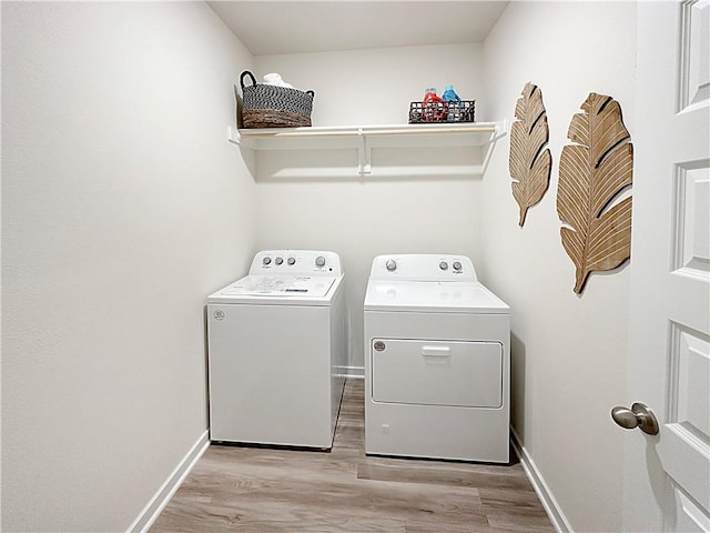 clothes washing area with washing machine and dryer and light wood-type flooring