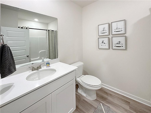 bathroom featuring vanity, curtained shower, wood-type flooring, and toilet