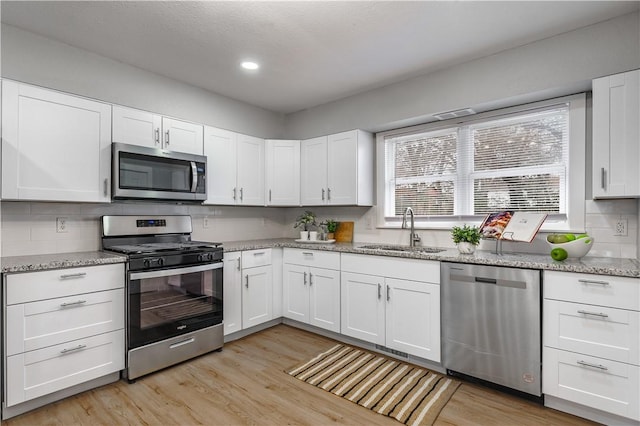 kitchen featuring stainless steel appliances, sink, light hardwood / wood-style flooring, and white cabinets