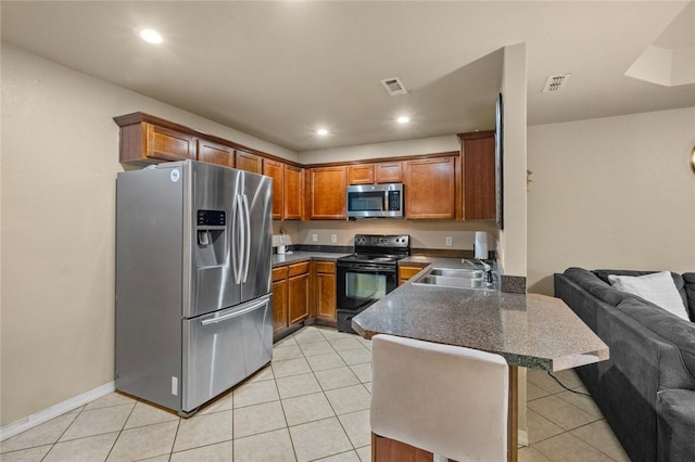 kitchen featuring appliances with stainless steel finishes, sink, light tile patterned floors, and kitchen peninsula