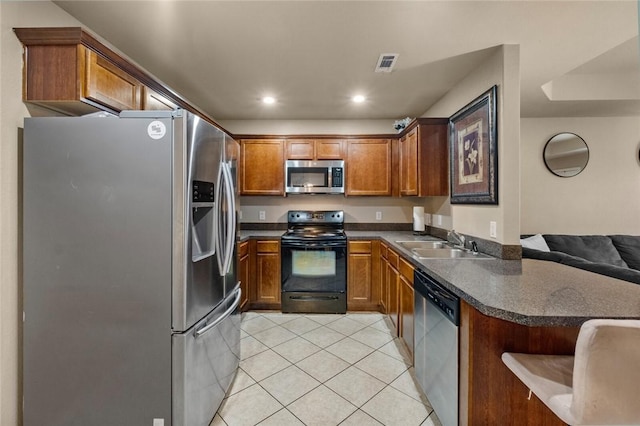 kitchen featuring sink, light tile patterned floors, a breakfast bar area, stainless steel appliances, and kitchen peninsula