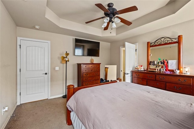 carpeted bedroom featuring ceiling fan and a tray ceiling