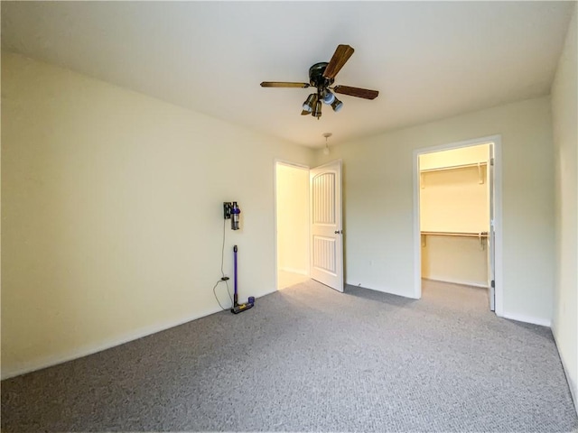 unfurnished bedroom with ceiling fan, a closet, a walk in closet, and carpet flooring