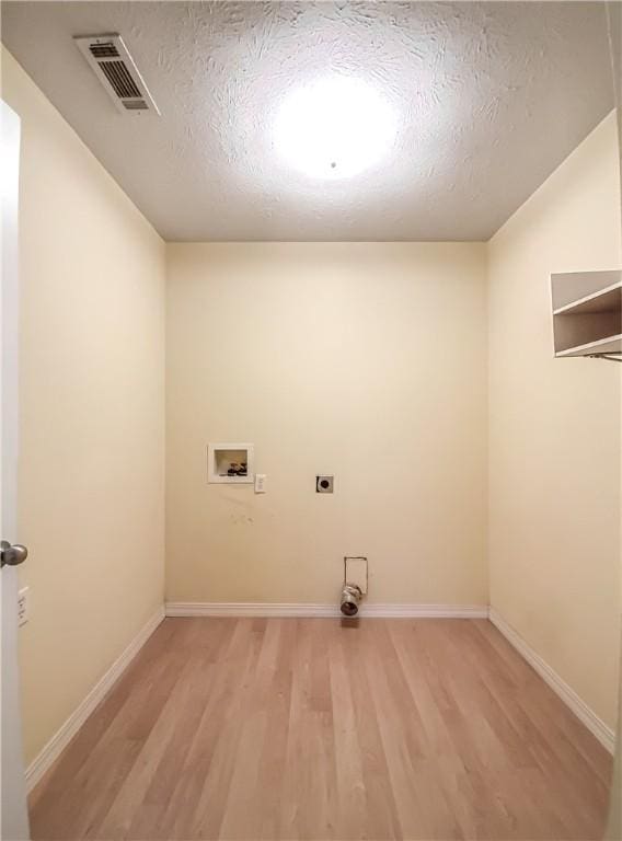 laundry area with washer hookup, a textured ceiling, light hardwood / wood-style flooring, and electric dryer hookup