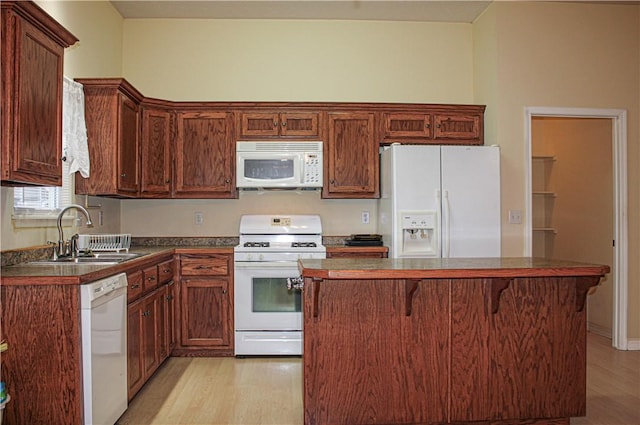 kitchen featuring dark countertops, white appliances, light wood-style floors, and a sink