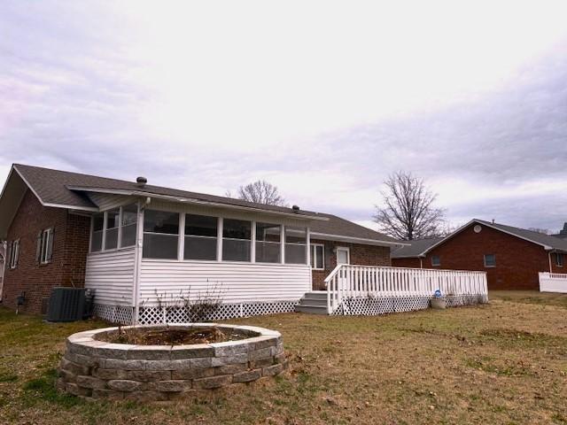 view of front facade with a wooden deck, a front yard, a sunroom, and central air condition unit