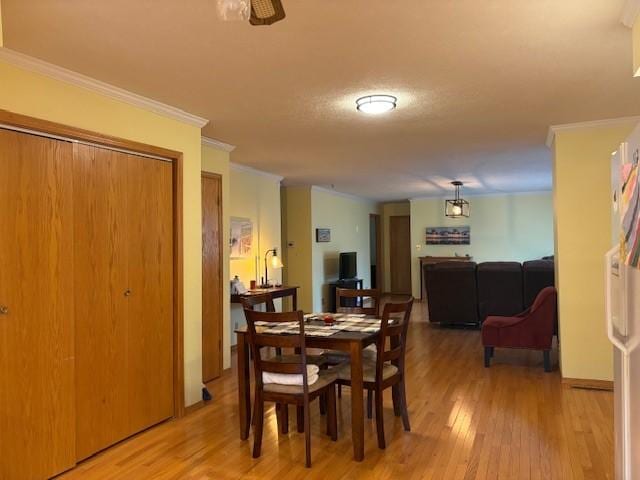 dining space featuring light hardwood / wood-style flooring, ornamental molding, and ceiling fan