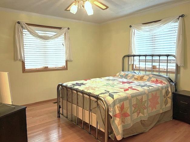 bedroom featuring ornamental molding, ceiling fan, and light wood-type flooring