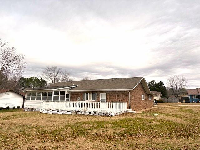 view of front of home with a wooden deck, a sunroom, and a front yard