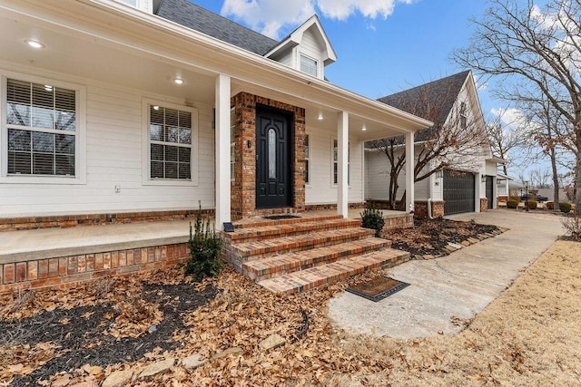 view of exterior entry with a garage and covered porch