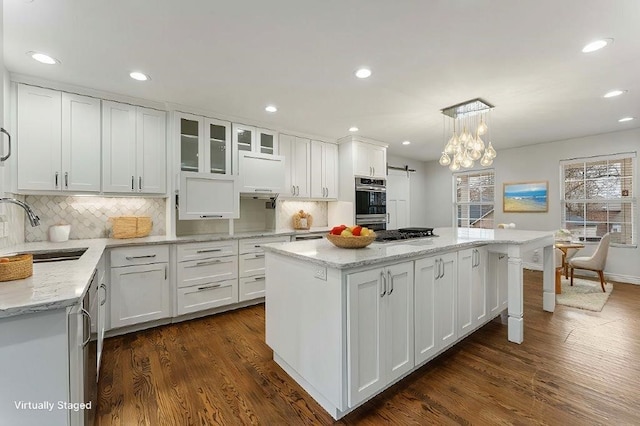 kitchen featuring a kitchen island, a sink, dark wood finished floors, and white cabinets