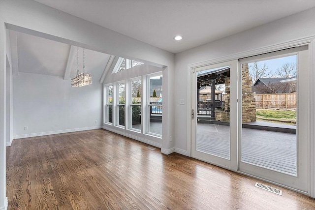doorway to outside with visible vents, baseboards, wood finished floors, vaulted ceiling, and a notable chandelier