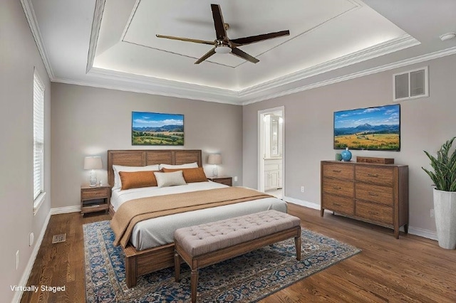 bedroom with a raised ceiling, visible vents, ornamental molding, wood finished floors, and baseboards