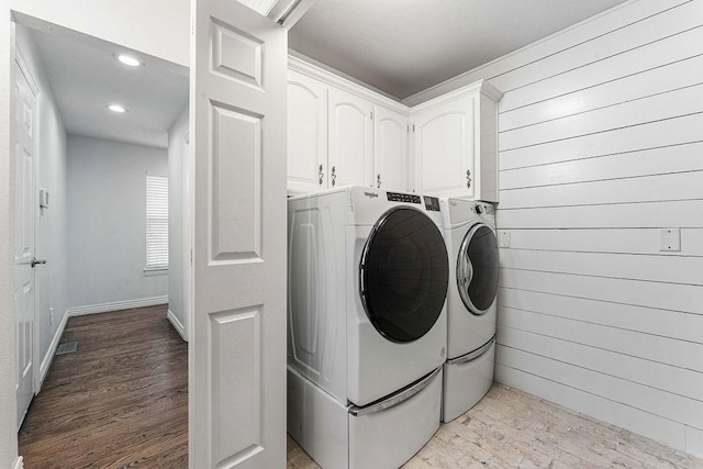 laundry room with cabinet space, light wood finished floors, wood walls, separate washer and dryer, and recessed lighting