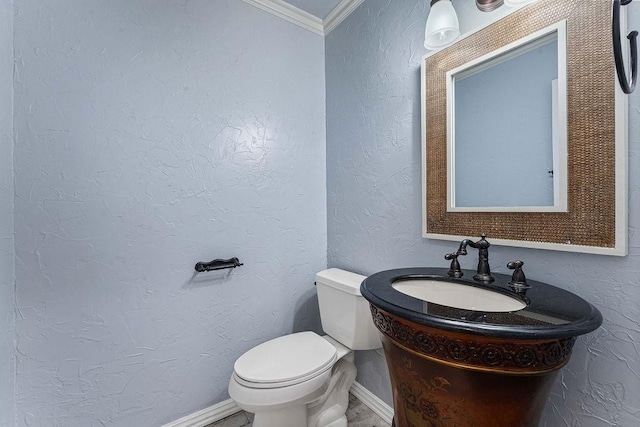 half bathroom with a textured wall, toilet, ornamental molding, vanity, and baseboards