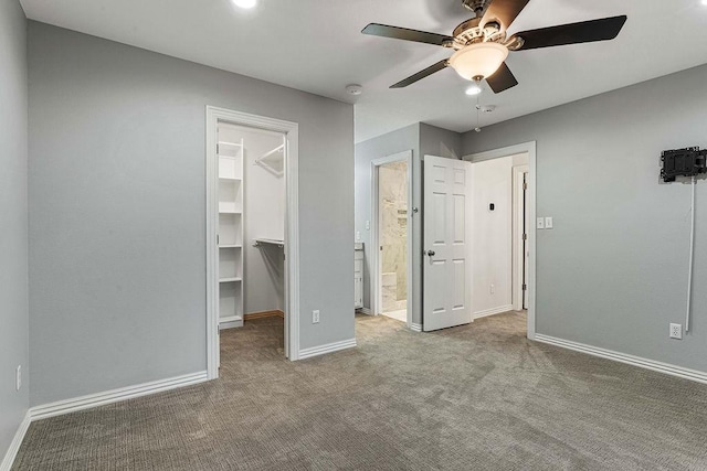unfurnished bedroom with baseboards, ensuite bathroom, carpet, a spacious closet, and a closet