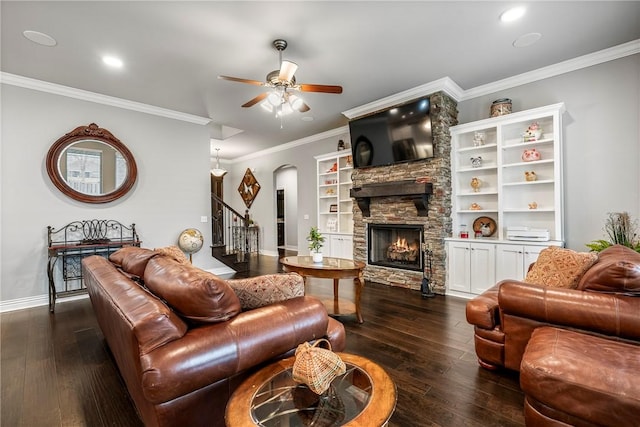 living room featuring ceiling fan, ornamental molding, dark wood-type flooring, and a fireplace