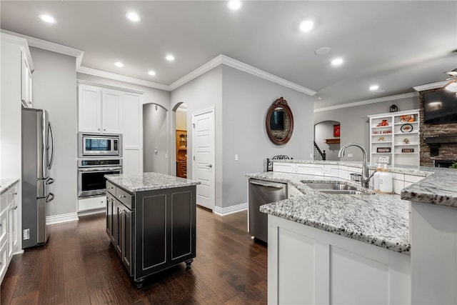 kitchen featuring stainless steel appliances, sink, light stone countertops, and a kitchen island with sink