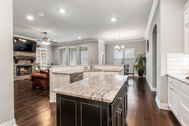 kitchen featuring sink, a stone fireplace, dishwasher, a kitchen island, and decorative light fixtures