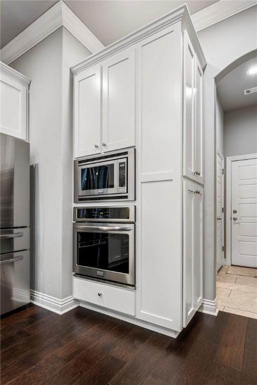 kitchen with crown molding, stainless steel appliances, dark hardwood / wood-style flooring, and white cabinets