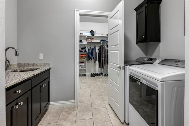 laundry room featuring sink, washing machine and dryer, cabinets, and light tile patterned flooring