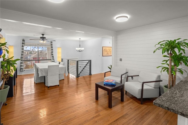 living room featuring ceiling fan with notable chandelier and light wood-type flooring