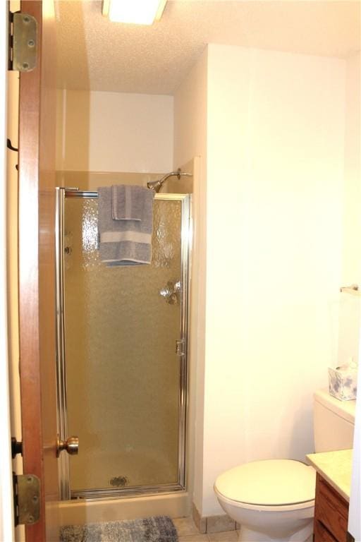 bathroom featuring walk in shower, vanity, toilet, and a textured ceiling