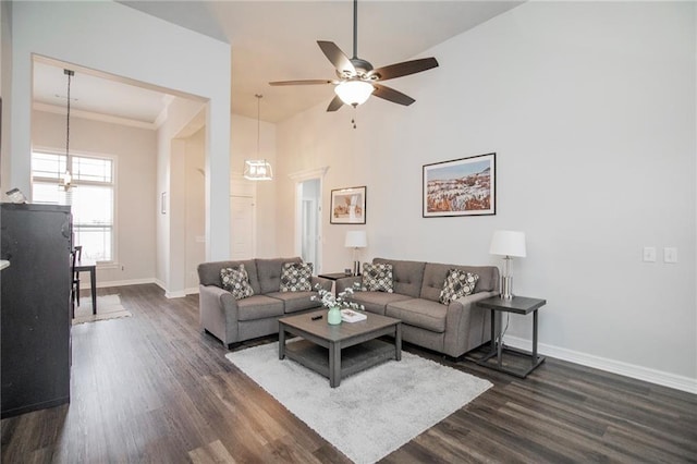 living room with ornamental molding, dark hardwood / wood-style floors, ceiling fan, and a towering ceiling