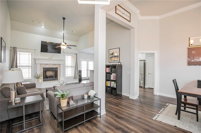 living room featuring dark wood-type flooring, a tiled fireplace, high vaulted ceiling, and a wealth of natural light