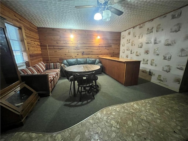 interior space featuring ceiling fan, carpet floors, and wood walls