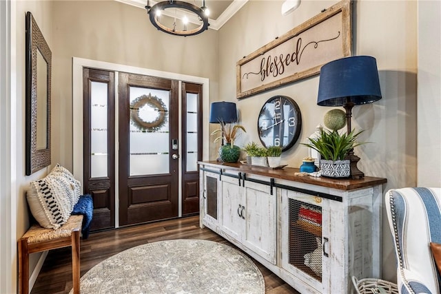 foyer entrance featuring crown molding, an inviting chandelier, and dark hardwood / wood-style flooring