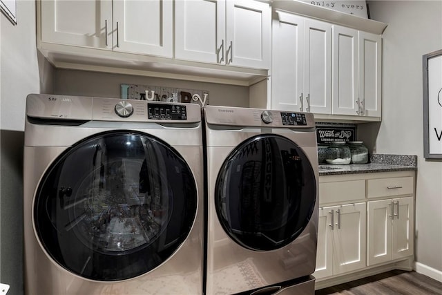 laundry room featuring cabinets, dark hardwood / wood-style floors, and washer and clothes dryer