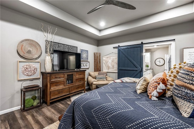 bedroom featuring a barn door, dark hardwood / wood-style floors, and ceiling fan