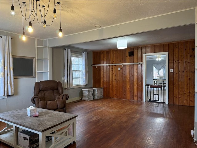 living area featuring dark hardwood / wood-style floors, a textured ceiling, and wood walls