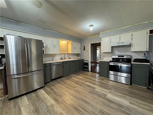 kitchen with stainless steel appliances, sink, hardwood / wood-style floors, and white cabinets