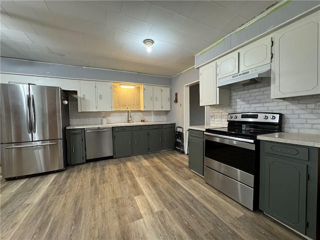 kitchen featuring sink, gray cabinets, appliances with stainless steel finishes, light hardwood / wood-style floors, and decorative backsplash