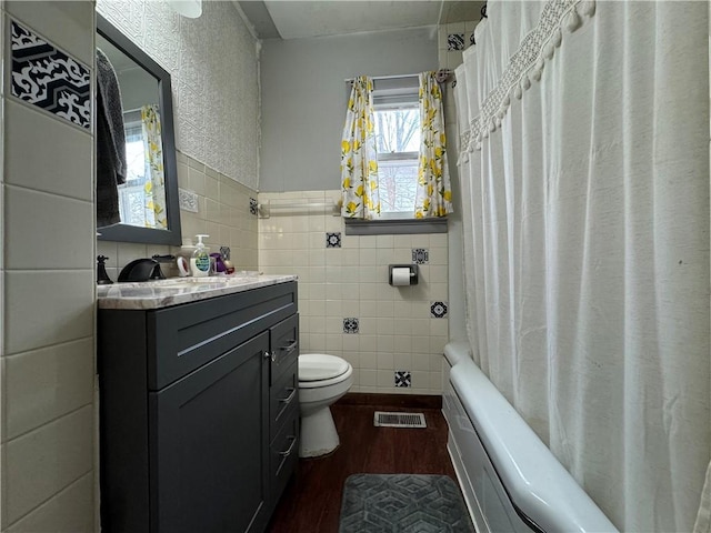 full bathroom with wood-type flooring, tile walls, vanity, toilet, and shower / bathtub combination with curtain