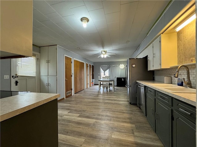 kitchen featuring dishwasher, sink, decorative backsplash, ceiling fan, and light hardwood / wood-style flooring