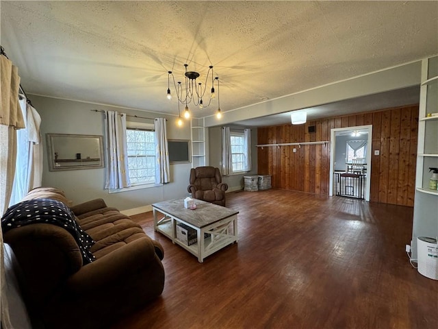 living room featuring an inviting chandelier, hardwood / wood-style floors, wooden walls, and a textured ceiling