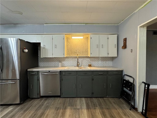 kitchen with dark wood-type flooring, sink, white cabinetry, stainless steel appliances, and decorative backsplash