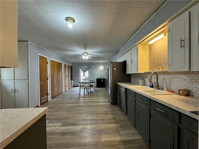 kitchen with tasteful backsplash, sink, stainless steel dishwasher, ceiling fan, and light wood-type flooring