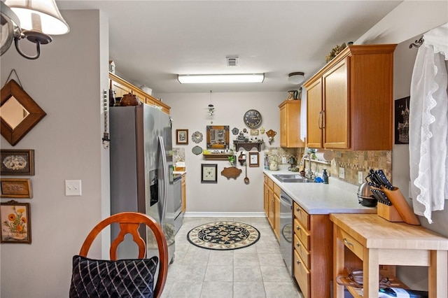 kitchen featuring sink, light tile patterned floors, hanging light fixtures, stainless steel appliances, and tasteful backsplash