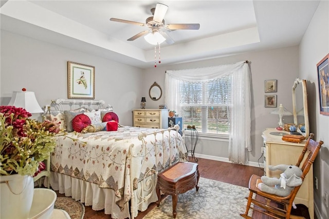 bedroom with a raised ceiling, ceiling fan, and dark hardwood / wood-style flooring