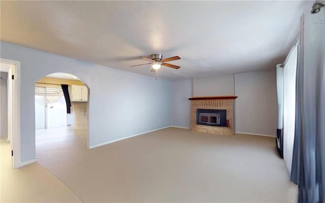 unfurnished living room with a brick fireplace, light colored carpet, and ceiling fan