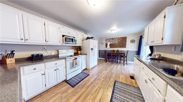 kitchen with white cabinetry, white appliances, light hardwood / wood-style floors, and sink