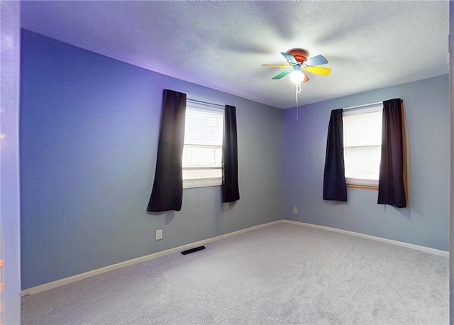 empty room featuring ceiling fan, carpet, and a textured ceiling