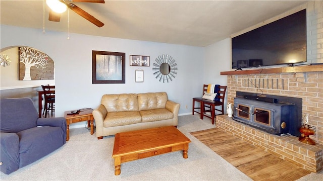 living room with carpet, ceiling fan, and a wood stove